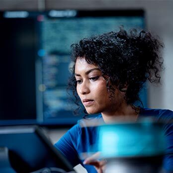 Woman on computer with screens behind her