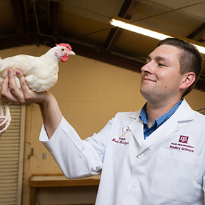 Brett Meisinger wearing his coaching and holding up a chicken