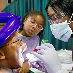 Dentist inspecting a young boy's mouth with a flashlight
