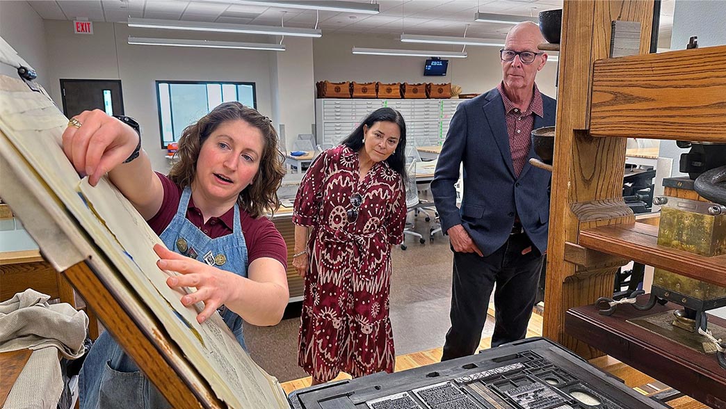 Maddie Keyser, Texas A&M's book arts and historic press room librarian, shows a period-accurate common press in the Evans Library Annex to Dr. Diana Gabaldon and her husband, Doug Watkins